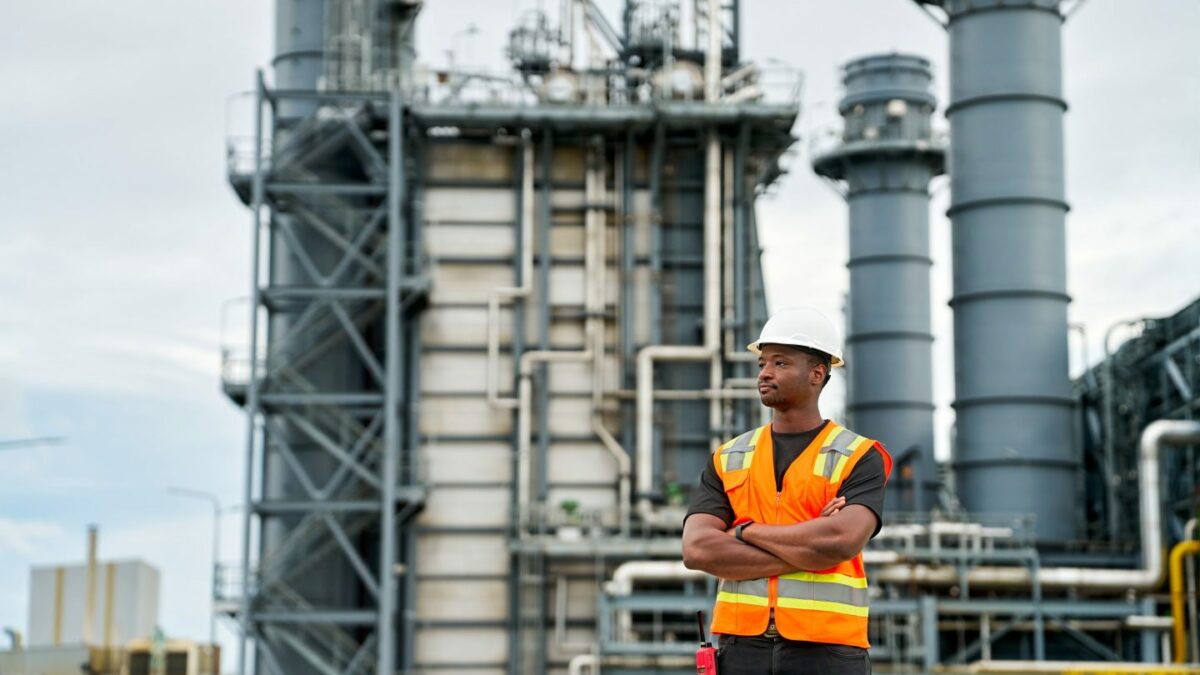 Young energy worker stands in front of power plant