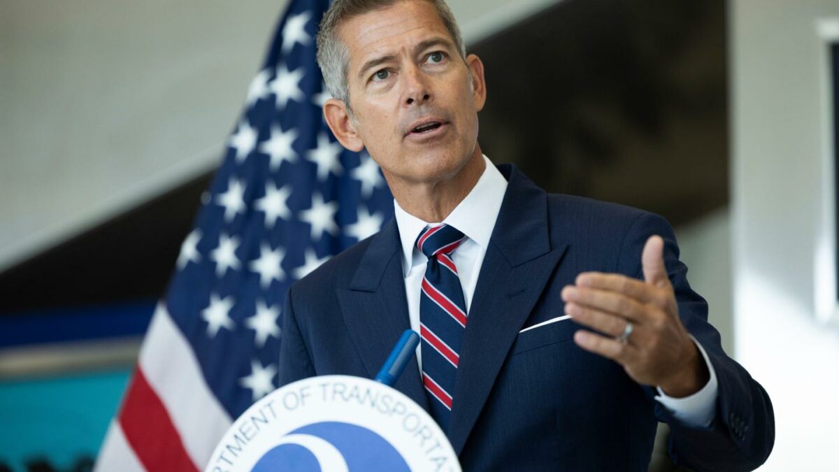 Sean Duffy speaks behind a podium. An American flag hangs behind him.