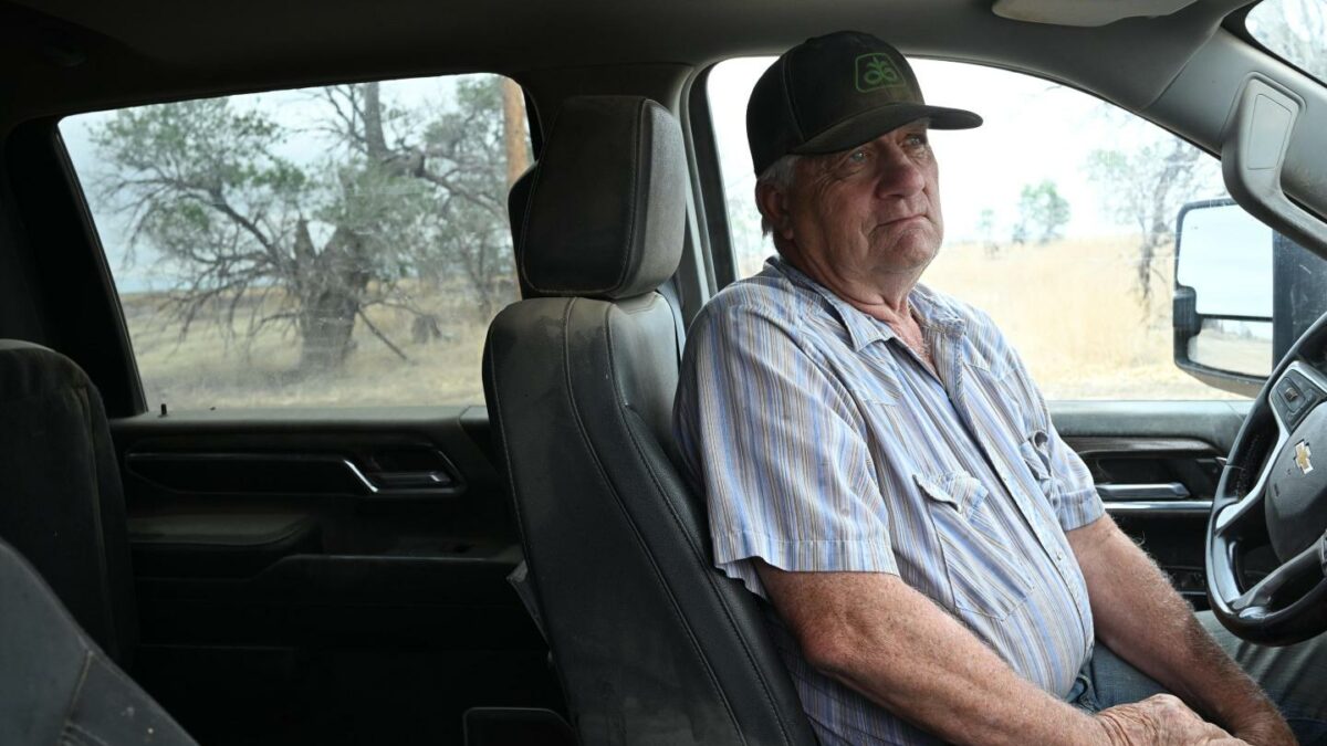 A man sits in the driver’s seat of a truck, frowning.