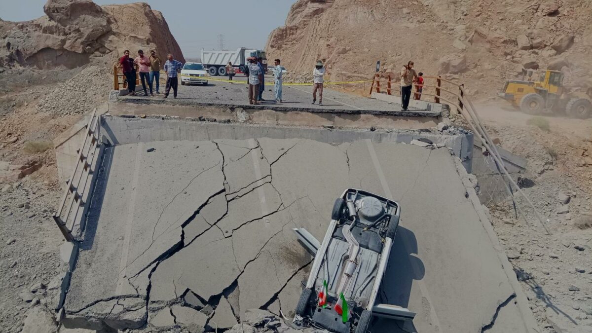 An overturned car sits on a section of a destroyed bridge after a strike in Hormozgan province, southern Iran, Saturday, July 18, 2026.