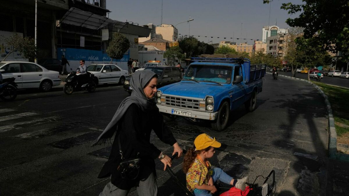 A woman crosses a street with a girl in downtown Tehran, Iran, Wednesday, July 22, 2026.