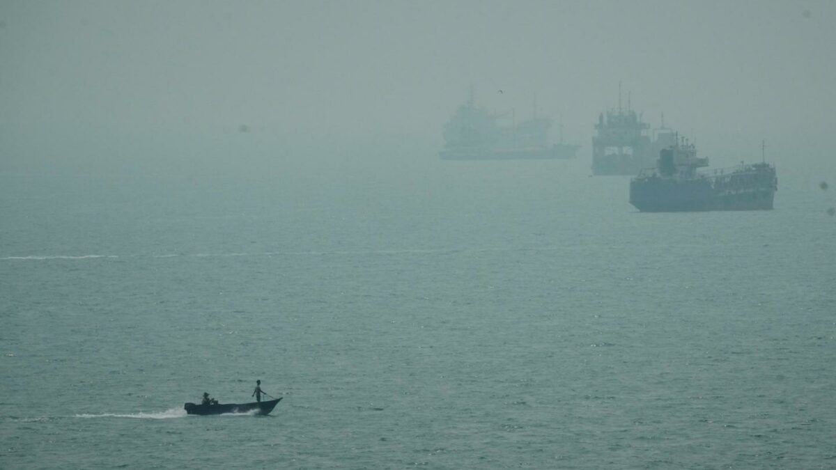 A motorboat travels past commercial vessels anchored amid haze in the Strait of Hormuz off Bandar Abbas, Iran, Monday, Sept. 7, 2026.