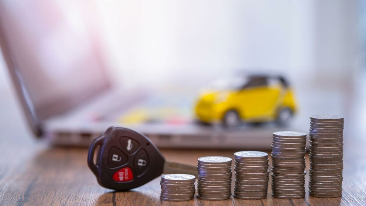 A tiny car on a table with keys and a stack of coins.