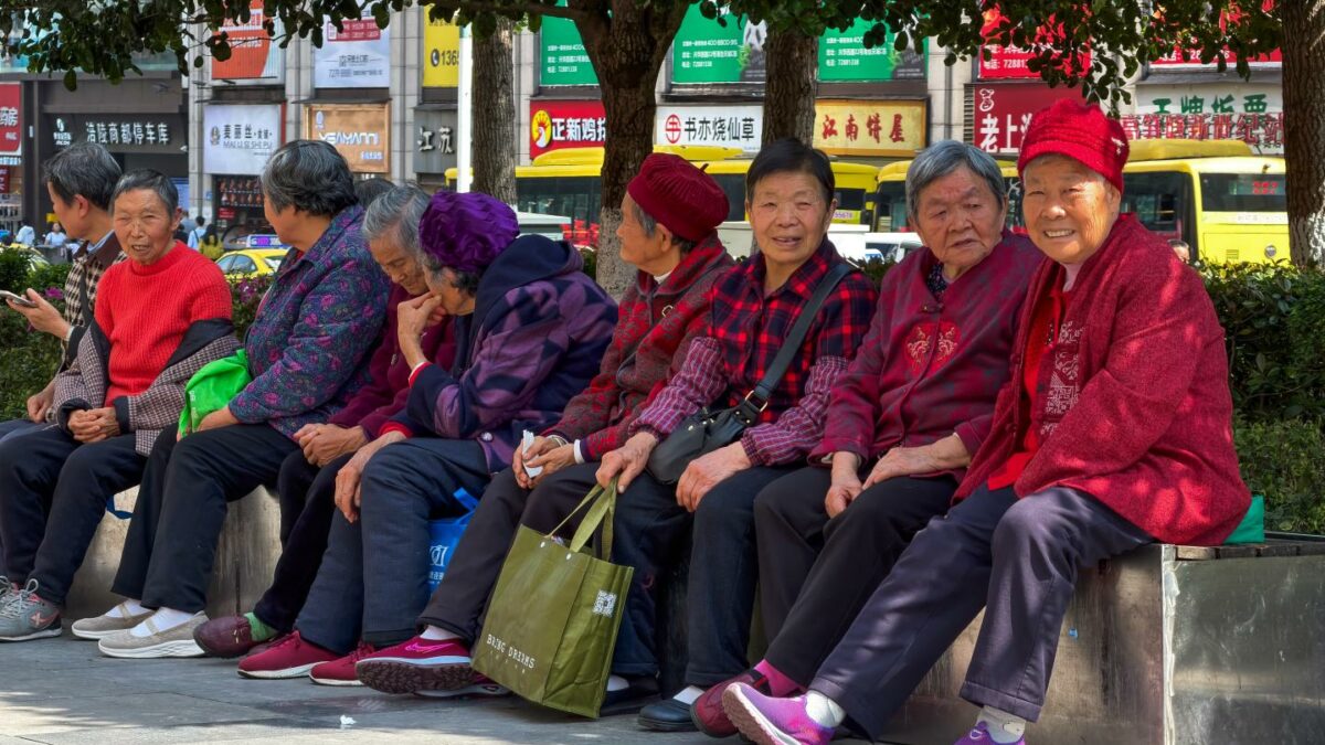 Elderly women sit together along a street under the shade of trees, chatting and resting on April 4, 2026, in Chongqing, China.