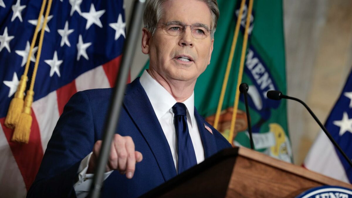 Scott Bessent speaks behind a podium and in front of an American flag.