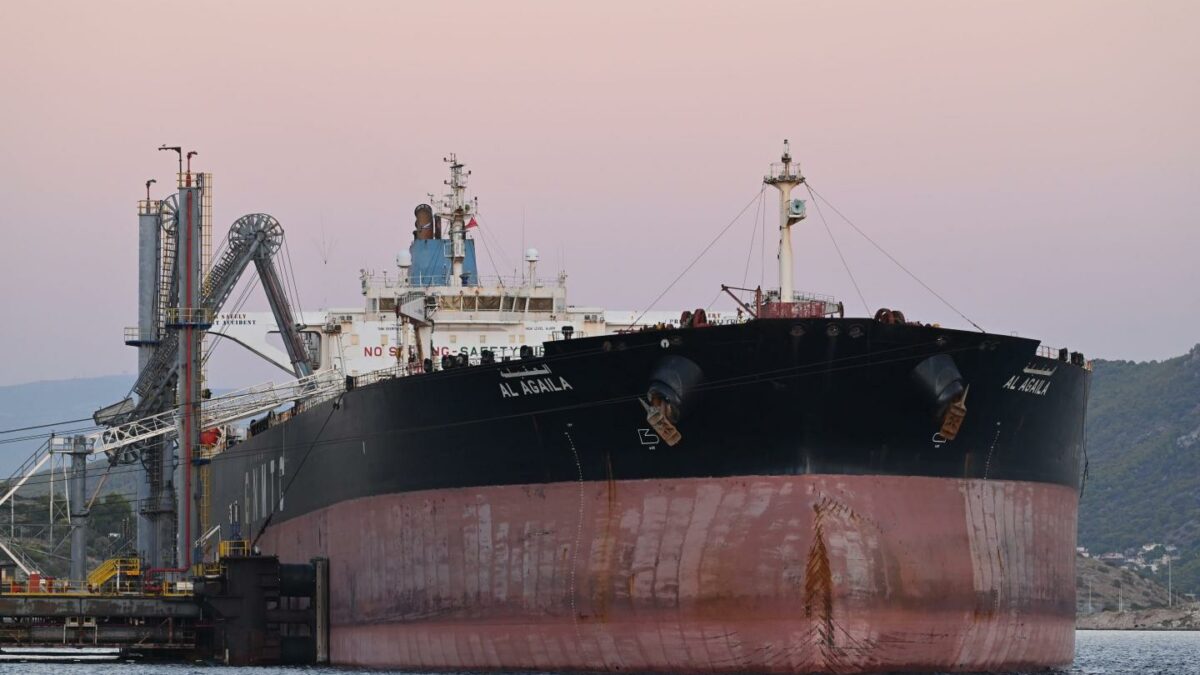 An oil tanker on the water in front of a setting sun.
