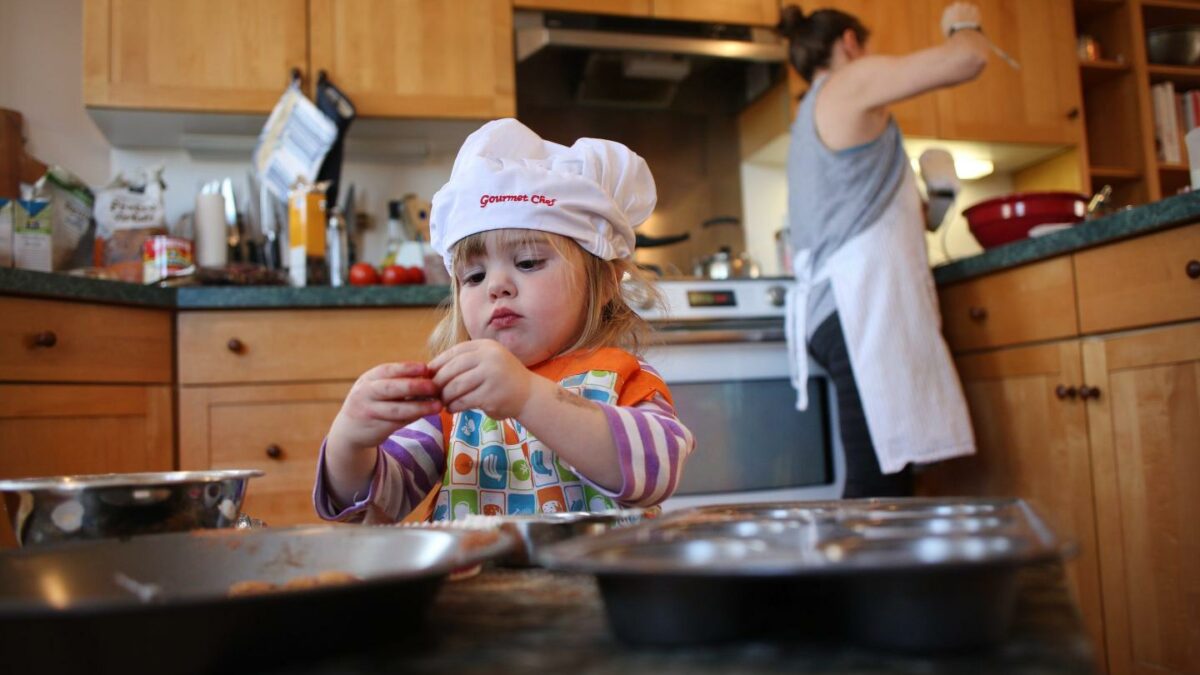 Photo of kid with mom working in the kitchen